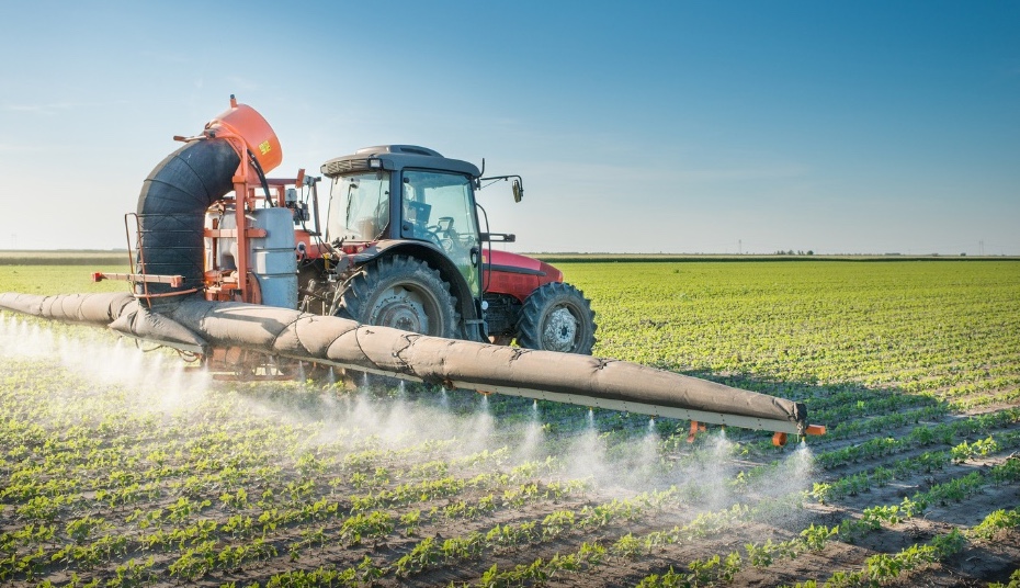 Traktor spritzt Spritzmittel auf Ackerfeld.